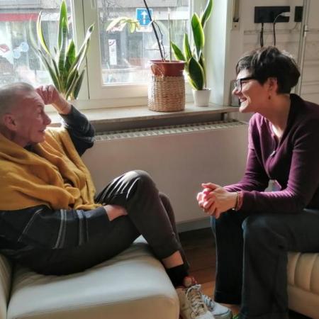 Twee mensen lachend en in gesprek op de zetel