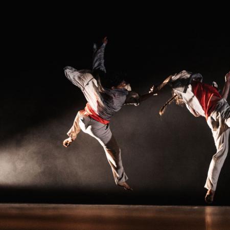 Roots compagnie 2022 twee dansers in sprong in theaterzaal, kostuum gevechtskunst