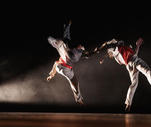 Roots compagnie 2022 twee dansers in sprong in theaterzaal, kostuum gevechtskunst